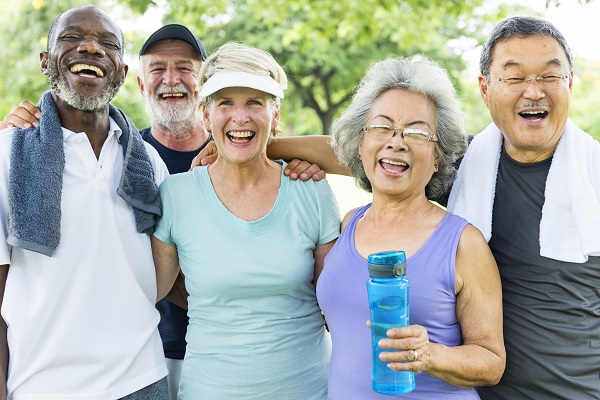 Group of five older people after exercise one with a water bottles and two with towels around their necks